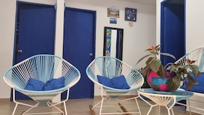 Una habitación con dos sillas de mimbre azules, un sofá blanco y una planta decorativa.