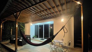 Un patio al aire libre con una hamaca, una mesa y sillas.