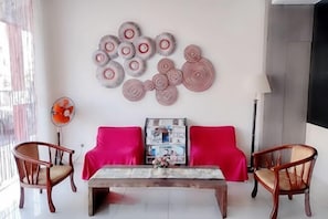 A living room with a sofa, two chairs, a coffee table, and wall art. - Seven Hotel (Putatan)