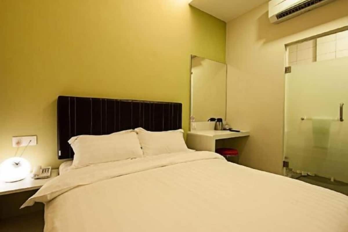 A hotel room with a bed, bedside table, lamp, and a mirror.