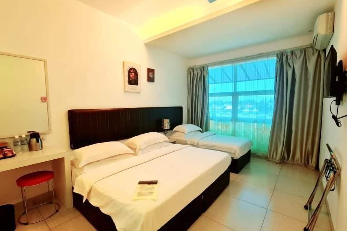 A hotel room with two beds, a desk, a chair, a window with curtains, and a television mounted on the wall.