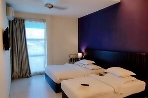 A hotel room with two beds, a TV, a window with curtains, and a headboard with a light. - Seven Hotel (Putatan)