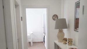Un pasillo con una consola blanca, una lámpara y elementos decorativos.
