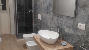 Un baño moderno con cabina de ducha de vidrio, lavamanos blanco y tocador de madera.