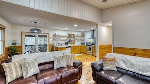 Un amplio salón con sofás de cuero, una zona de comedor y una cocina.