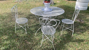 A round metal table with a white pedestal base, surrounded by four metal chairs with a lattice design. - Escape to Paradise at Venus Lodging House, Alto Boquete (Alto Boquete)