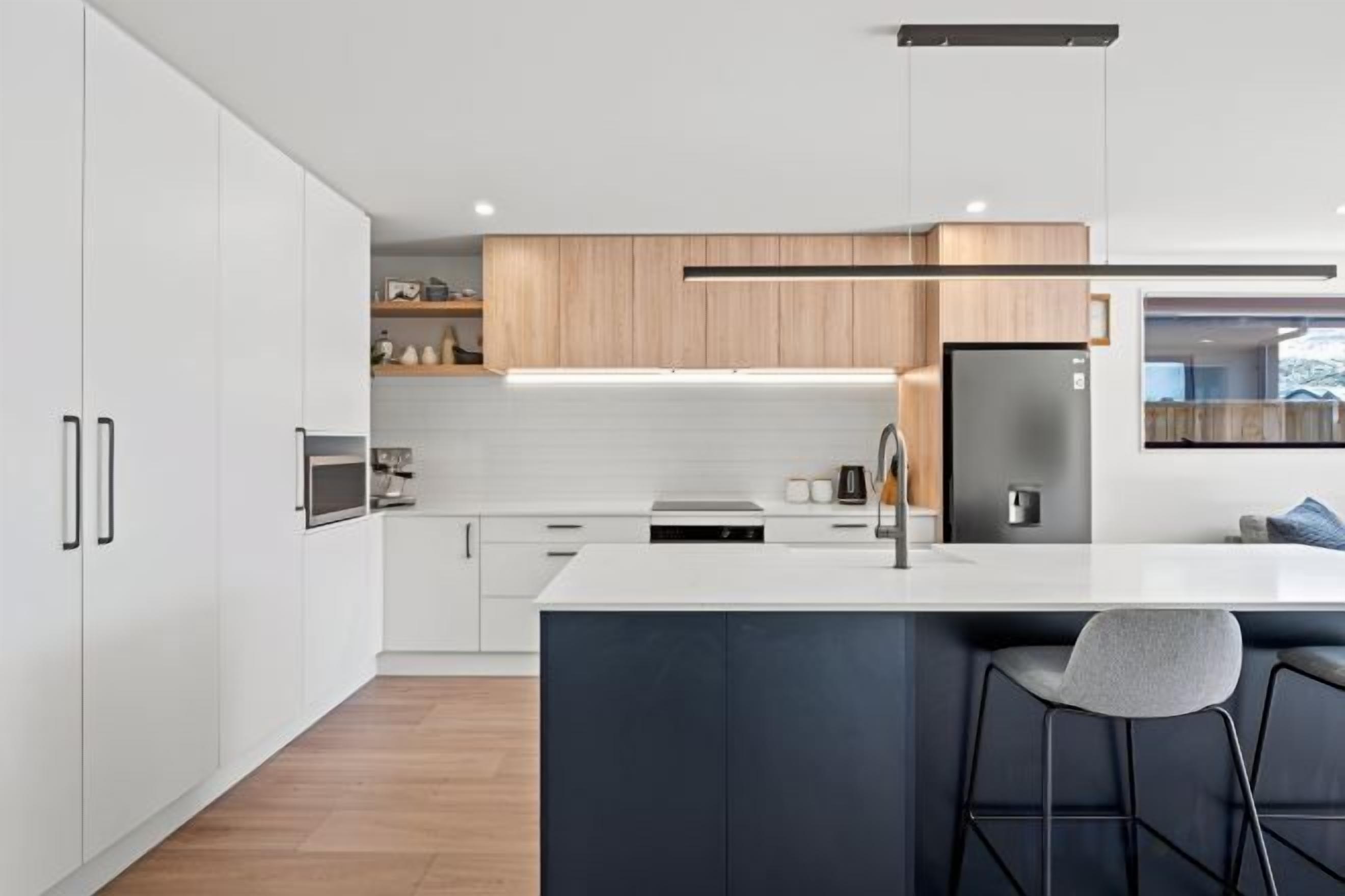 Una cocina moderna con armarios blancos, una isla central y un horno empotrado.