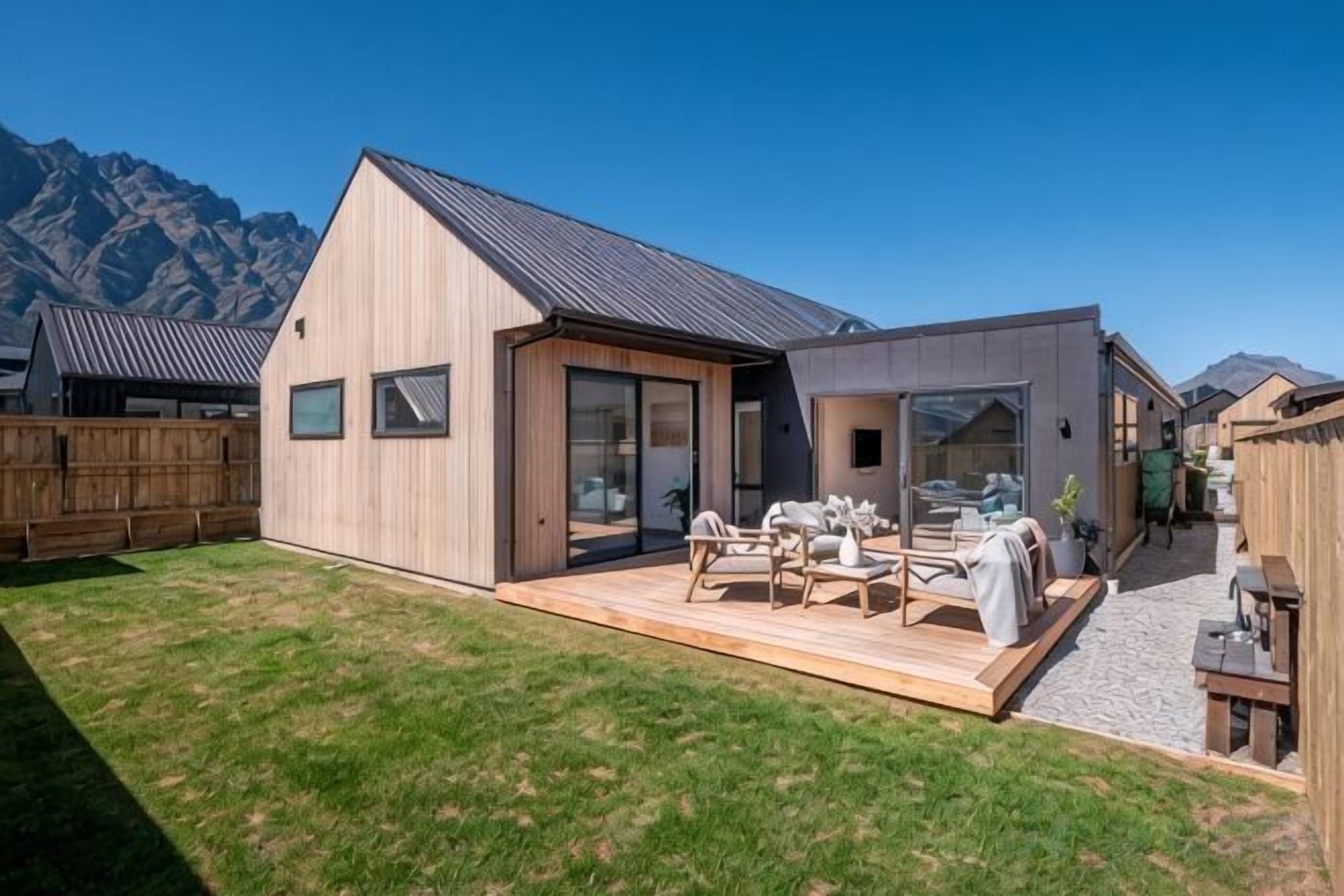 Una casa moderna con terraza, patio y montañas al fondo.