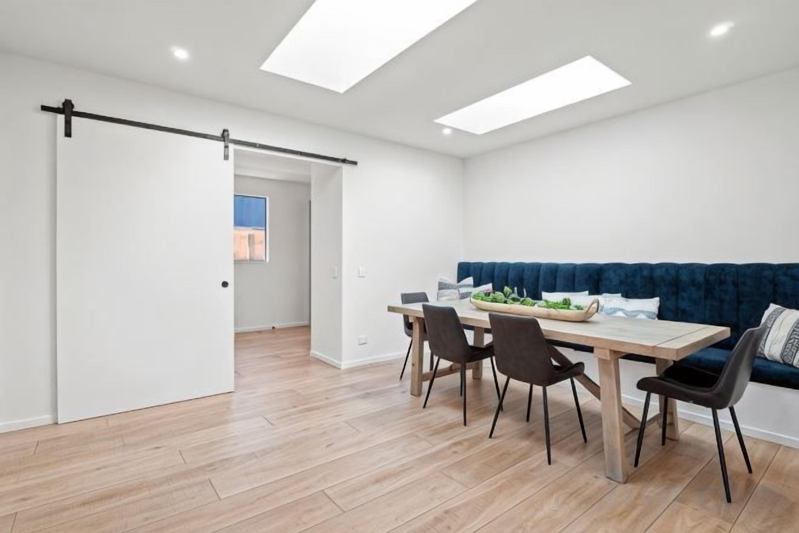 A modern dining area with a wooden table, four chairs, and a blue sofa.