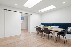 Een moderne eetruimte met een houten tafel, vier stoelen en een blauwe bank.