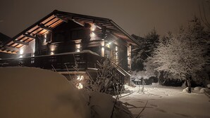 A wooden cabin with a sloped roof and multiple windows, surrounded by snow-covered ground and trees. - Le 1853, charming 5* chalet with contemporary interior. Nature, peace and quiet. (Chamonix-Mont-Blanc)