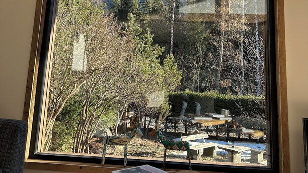 A room with a large window offering a view of snow-capped mountains, a wooden ceiling, and a table with books and a cup. - Le 1853, charming 5* chalet with contemporary interior. Nature, peace and quiet. (Chamonix-Mont-Blanc)