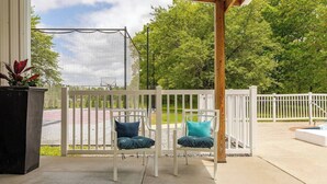Un patio abrité avec deux chaises blanches et une petite piscine.