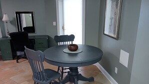 Un coin repas comprenant une table ronde, deux chaises, un bol décoratif, une lampe, un miroir et un meuble.