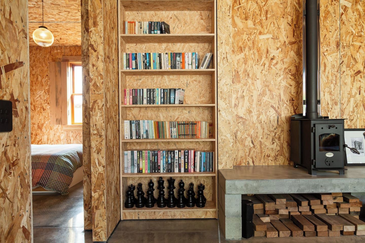 A cozy room with a wooden bookshelf, a fireplace, and a bed with a patterned blanket.