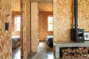A room with exposed wooden walls, a bed, a fireplace, and a window.