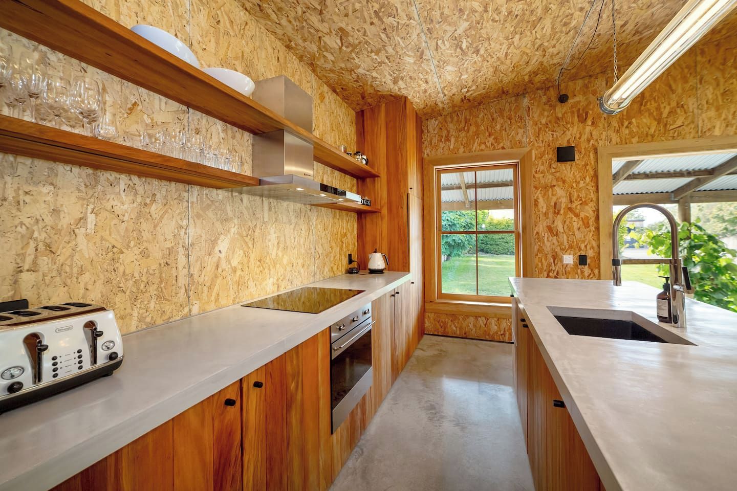 Una cocina con armarios de madera, estufa integrada y ventana con vistas al exterior.