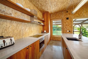 A kitchen with wooden cabinetry, a built-in stove, and a window providing a view of the outdoors.