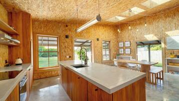 A modern kitchen with wooden cabinetry, a central island, and large windows.