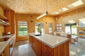 A modern kitchen with wooden cabinetry, a central island, and large windows.