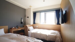 Une chambre d’hôtel avec deux lits, un bureau, une télévision et une fenêtre avec des rideaux.