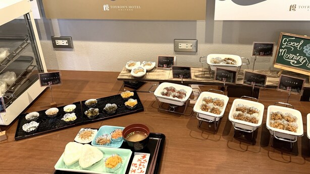 Un buffet proposant divers plats et un panneau noir sur lequel est écrit : « Bonjour ».