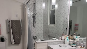 Ein Badezimmer mit Dusche, Toilette, Waschbecken und Spiegel.