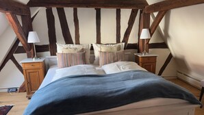 Ein Schlafzimmer mit einem Bett, zwei Nachttischen, einer Lampe und einer Holzbalkendecke.