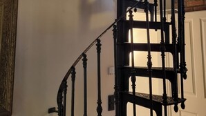 Eine Wendeltreppe mit Holzvertäfelung und schwarzen Geländern, die zu einer oberen Etage führt.