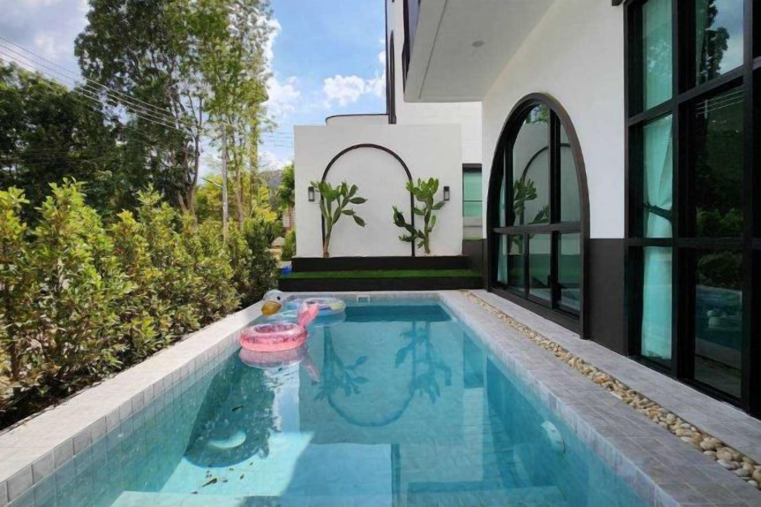A swimming pool with a tiled edge, surrounded by a low wall and plants.