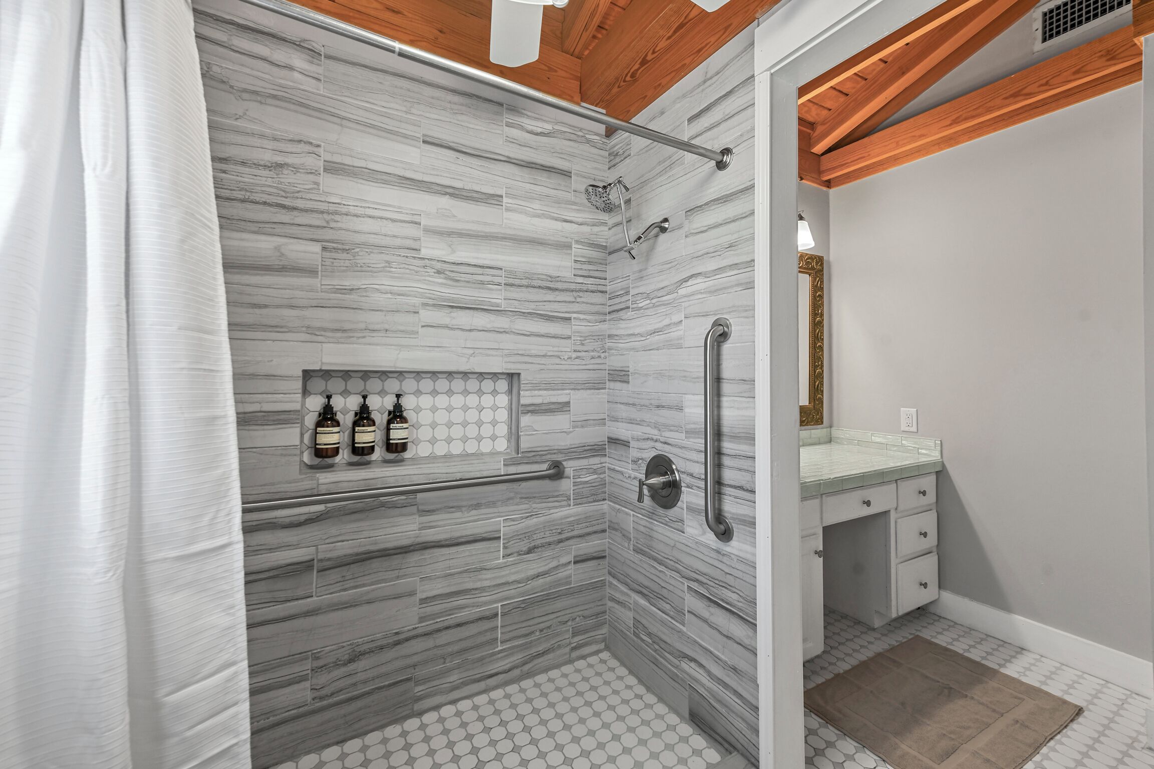Un bagno con doccia, un mobile lavabo con specchio e un portasciugamani.