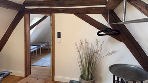 A room with exposed wooden beams, a hanging light fixture, a small table, a chair, a potted plant, and a painting on the wall. - Schmuckstück Maikammer - unique atmosphere with that certain something Whg. 5 (Maikammer)