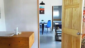A room with a wooden desk, a chair, and a door leading to another room. - La Casita Azul - Cozy Casita with Large Backyard in Marfa, TX (Marfa)