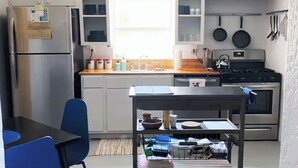 A compact kitchen with a refrigerator, stove, and a dining area with a table and chairs. - La Casita Azul - Cozy Casita with Large Backyard in Marfa, TX (Marfa)