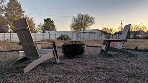 Two Adirondack chairs, a fire pit, and a gravel ground. - La Casita Azul - Cozy Casita with Large Backyard in Marfa, TX (Marfa)