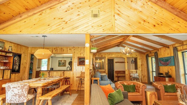 A wooden cabin interior with a dining area, living room, and kitchen.