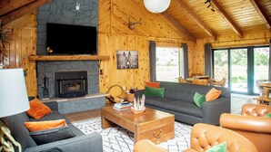 A spacious living room with a stone fireplace, a large flat-screen TV, and a cozy seating area with sofas and a coffee table.
