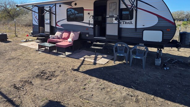 A recreational vehicle with a slide-out awning, a sofa, and a table. - Cozy RV in peaceful Sandia with WiFi, AC,Lake Corpus Chrisit Access nearby (Sandia)