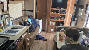 A compact RV kitchen with a stove, sink, and a dining area. - Cozy RV in peaceful Sandia with WiFi, AC,Lake Corpus Chrisit Access nearby (Sandia)