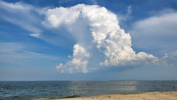 Ein Strand mit blauem Himmel und großen Wolken.
