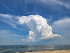 A beach with a clear sky and large clouds.