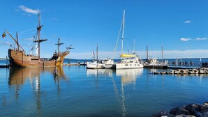 Ein Hafen mit einem großen Holzschiff und mehreren kleineren Booten, die vertäut sind.