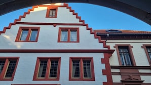 A traditional European building with a steeply pitched roof and red window frames.