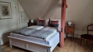 A bedroom with a large bed, a wooden chair, a nightstand, and a small table.