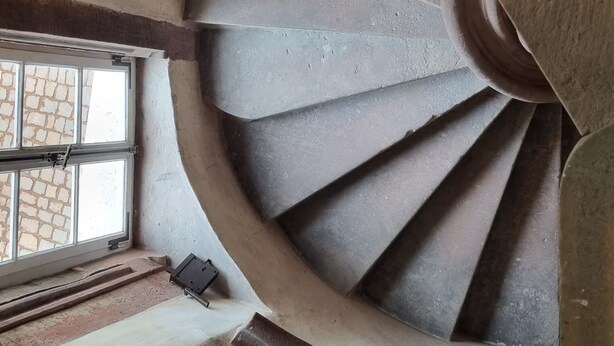 A spiral staircase with a circular design, leading to an upper level.