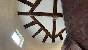 A high ceiling with exposed wooden beams and a small window.