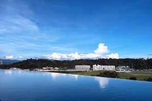 A large body of water with a clear sky and a distant view of buildings and a forested hill. - Restful Respite Tanjung Aru Inifnity Pool 2BR (Kota Kinabalu)