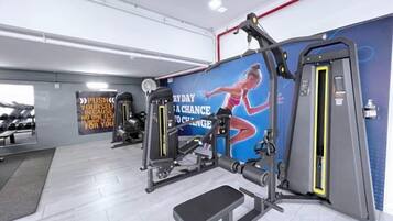 A gym with exercise equipment, a wall with motivational text, and a bench.