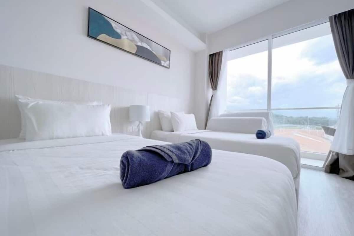 A hotel room with two beds, a large window with a view, and a painting on the wall.