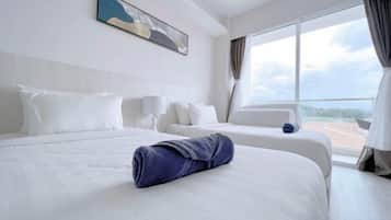 A hotel room with a large bed, a smaller bed, a window with a view, and a painting on the wall.